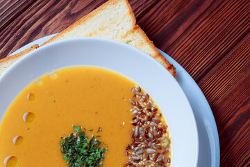 Vegetable soup with bread on wooden tray. White bowl on dark plank background. Top view. Copy space.