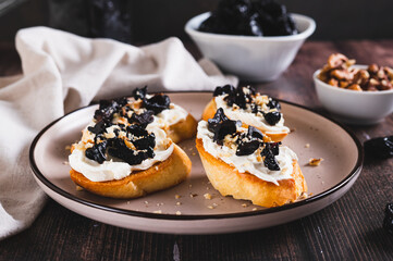 Delicious toasts with ricotta and prunes on a plate on the table