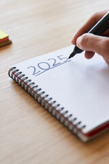 New year's resolutions. Hand writing 2025 text in notebook 