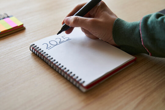 New year's resolutions. Hand writing 2025 text in notebook 