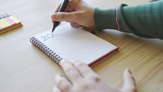 New year's resolutions. Hand writing 2025 text in notebook 