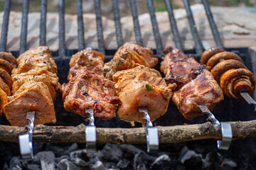 Grilled pieces of pork meat and mushrooms on metal skewers. Shashlik or shish kebab prepared on barbecue grill over hot charcoal with grilled vegetables.