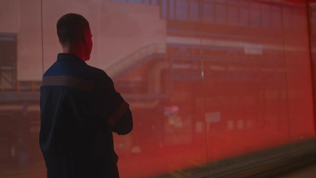A man in a fireproof suit stands in the smelting shop of a metallurgical plant.