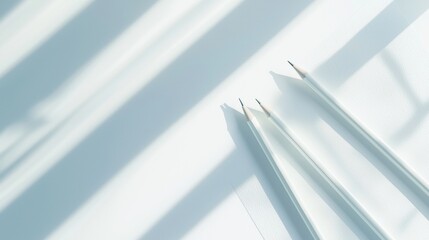 Obraz premium Three pencils are sitting on a white surface, casting shadows on the wall