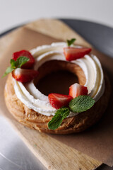 choux pastry creamy cheese cake with mint and strawberries on a craft background