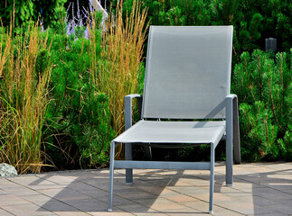 szary leżak w ogrodzie, leżak ogrodowy, puste leżaki ogrodowe, gray deckchair in the garden, garden deckchair, empty garden sunbeds, sitting area © kateej