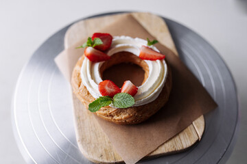 choux pastry creamy cheese cake with mint and strawberries on a craft background