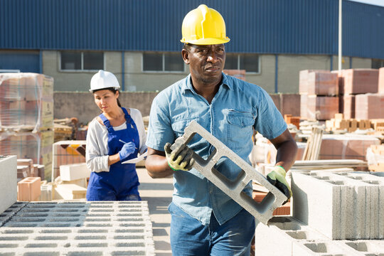 African male sellerman is calculating bricks before selling in construction store