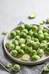Fresh brussels sprouts in a plate on a light gray background with napkin close up. Vegetarian healthy food concept.