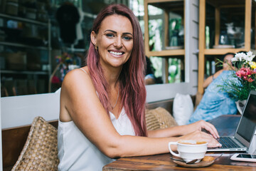 Happy female using laptop in cozy cafe