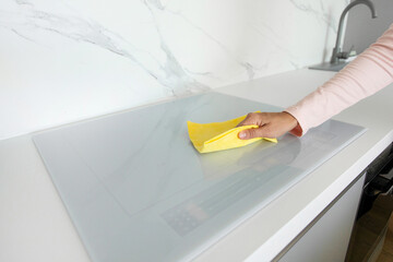 Woman housewife cleaning induction stove, doing house chores in modern light kitchen, closeup shot