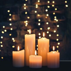A group of white pillar candles provides a cozy, warm glow against a dark background featuring festive, golden bokeh Christmas string lights.
