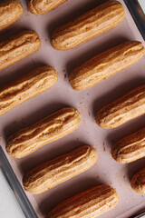 golden brown eclairs on a pink baking sheet