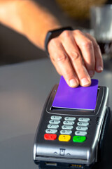 Person tapping credit card on payment terminal for contactless payment