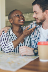 Lovely multiracial couple hugging and enjoying meeting at table in cafe