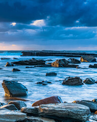 Moody sunrise seascape with clouds at the rocky inlet © Merrillie