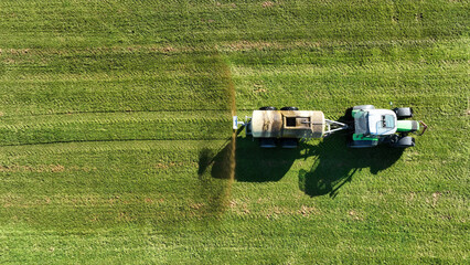 Drohnenaufnahme von einem Traktor der Gülle oder Jauche auf einem Feld ausbreitet