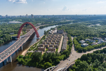 Aerial view of the Moscow River with the soaring bridge and lush greenery in the urban landscape during a sunny day in summer