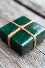 A green gift box tied with twine on a wooden table