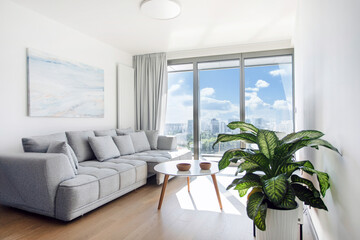 Serene cozy and light living room featuring white and grey furniture, soft accents, and lush...