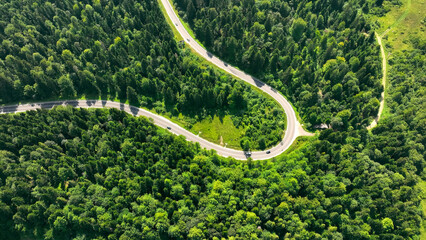 Aerial View of Serpentine Road through Lush Forest. A winding serpentine road cutting through...