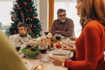 Family sitting at table enjoying christmas dinner together