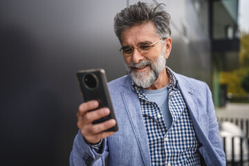 senior concentrated man use mobile phone in front black background