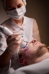 A man is currently undergoing a specialized facial treatment within a serene spa setting