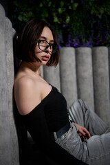 Fototapeta premium A Stylish Woman is Posing Confidently in a Fashionable Outfit While Relaxing on a Grey Couch