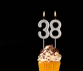 Birthday cupcake on black background - Number 38 shaped candles.