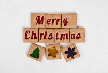 Merry Christmas. Ginger square cookies with red marmalade filling in the shape of the words Merry Christmas and tree, star, snowflake. White background. Top view