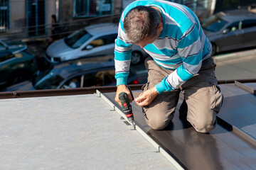 Roofer assembles sheet metal on the roof. Construction workers - installation assembly of new roof....