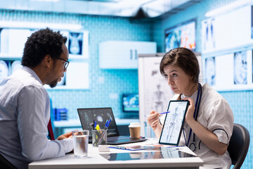 Doctor and patient interaction in a medical consultation room, featuring a tablet screen with medical results and x ray diagnosis, Highlighting technology in healthcare industry.