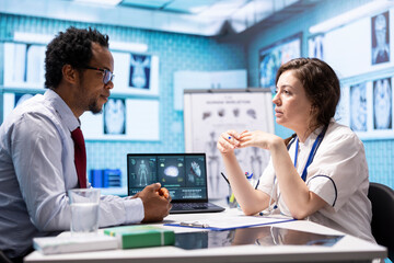 Physician presenting x ray imaging for the right diagnostic during check up, explaining the lab test results and treatment at medical consultation. Medic showing examination results in cabinet.