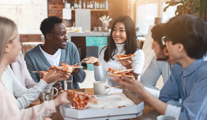 Cheerful international colleagues eating take away food in office during lunch break