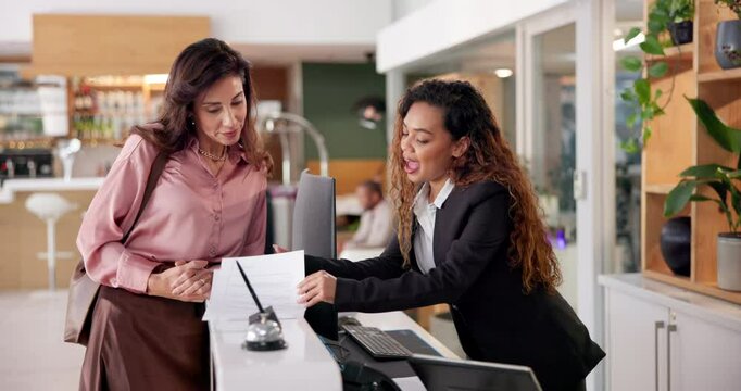 Women, customer and hotel receptionist with explaining for paperwork, agreement and contract. People, employee and client with document at help desk for hospitality, accommodation and reservation