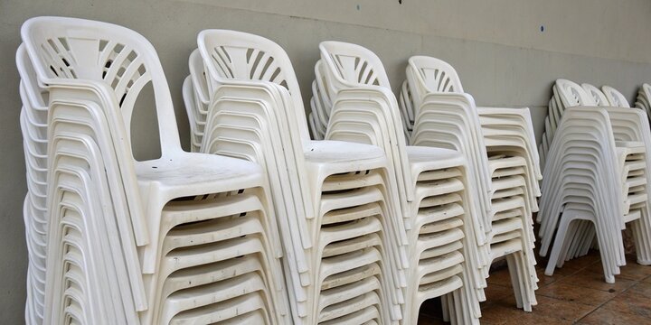 Conjunto de sillas de pl&aacute;stico blancas apiladas, ideal para eventos, exteriores y espacios sociales.