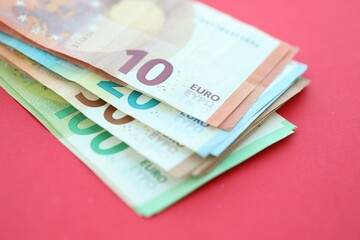 Big amount of one hundred, twenty, ten and fifty euro money bills on red background