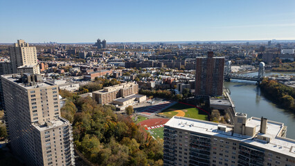Obraz premium This location in the Bronx offers stunning views of lush greenery, a picturesque lake, and urban structures. Framed by the river, it showcases iconic bridges and the New York City skyline 