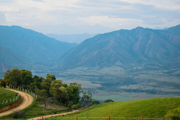 Majestic Colombian Countryside, A panoramic view of the stunning Colombian countryside, featuring rolling hills and majestic mountains in the background. The vibrant green fields and clear blue skies 