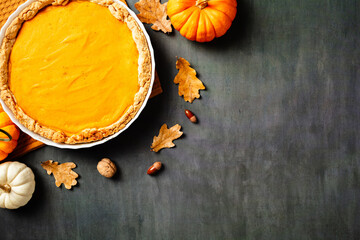 Flat lay pumpkin pie surrounded by fall leaves and decor. Perfect for seasonal recipes,...