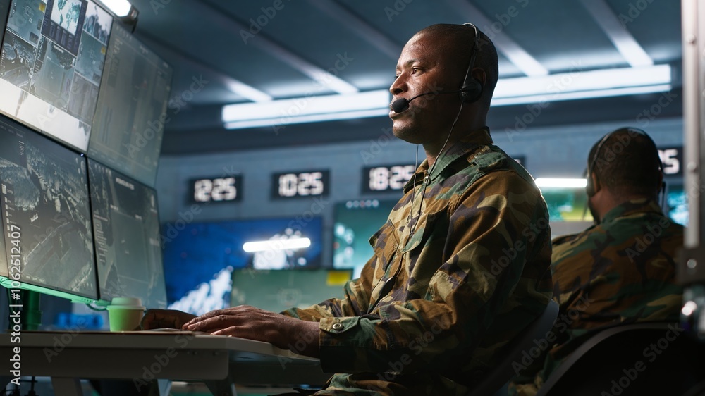 Poster army specialist working in war room operating surveillance tech, evaluating target data, talking in 