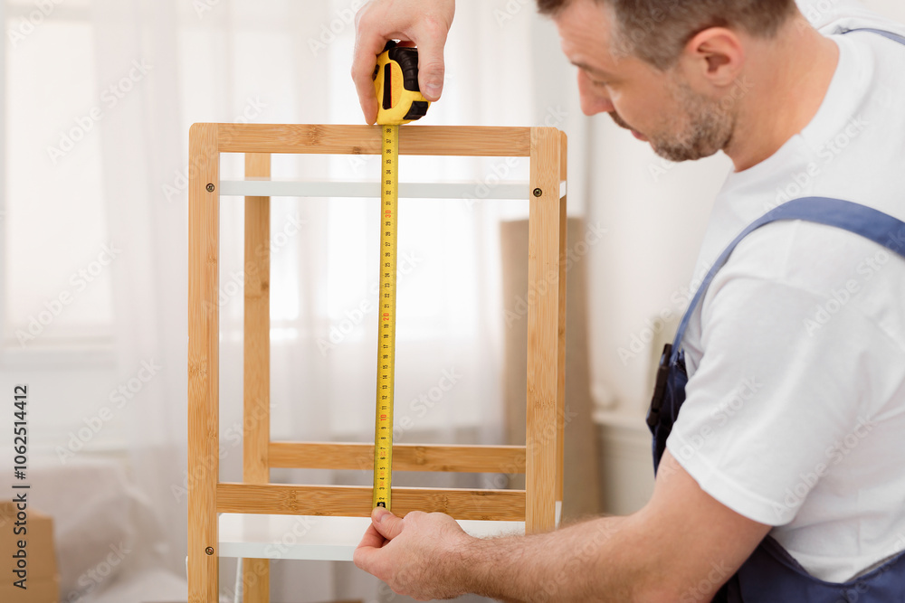 Poster making furniture. professional carpenter measuring shelf with tape working indoor. selective focus, 