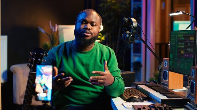 Guitarist instructor hosting guitar lessons online using a mobile phone, recording tutorial for master class. Artist musician explains acoustic instrument accords, assistance for beginners. Camera A.