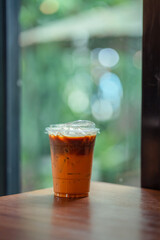Glass of iced milk tea with coffee on woodden. table in coffee shop.