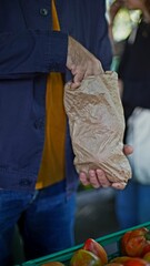 an elderly man holds a paper bag of tomatoes in his hands at a farmer's market in Lisbon