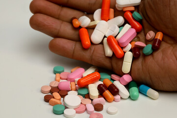 Close-up of a hand holding a handful of multi-colored medicines. Pharmacotherapy concept in pediatrics, pediatric medicine, medicinal products.