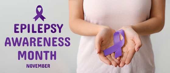 Woman with beige ribbon on light background, closeup. Uterine cancer awareness concept