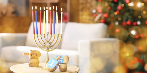 Menorah with burning candles and dreidels for Hanukkah celebration on table in living room, closeup
