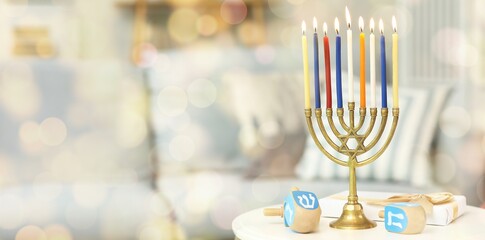 Burning candles, gift and dreidels on table at home. Hanukkah celebration